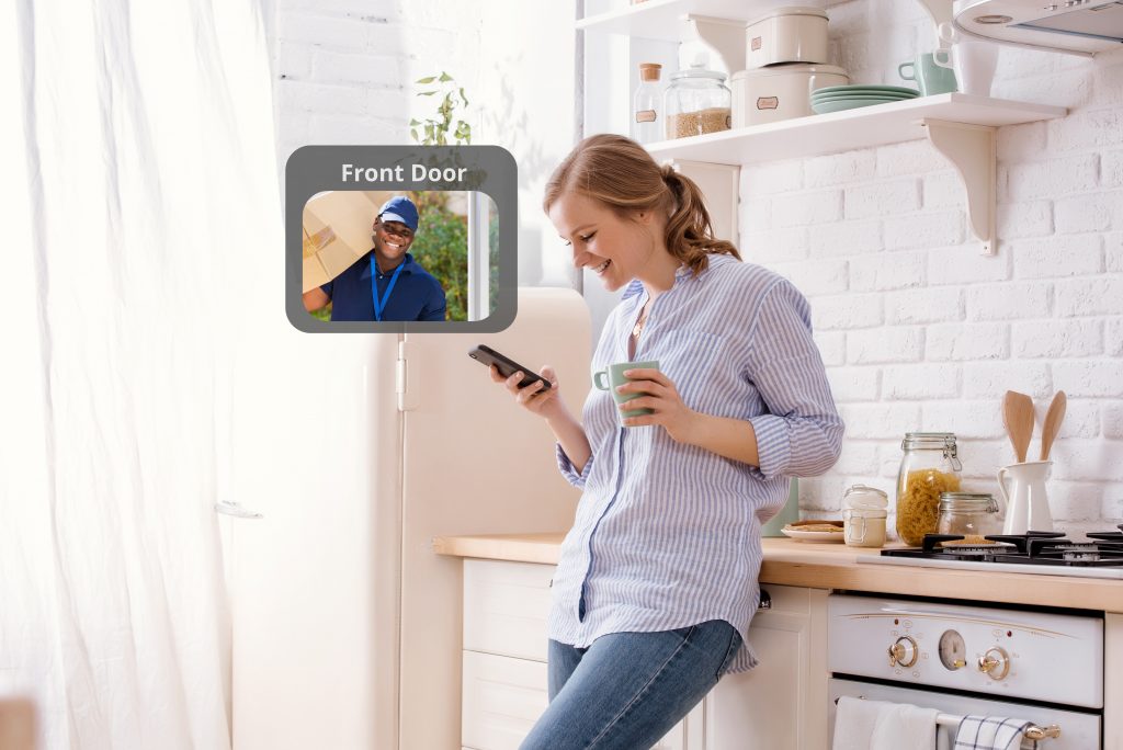 Happy woman looking at phone in kitchen to see front door visitor